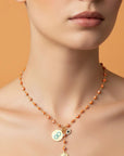 Necklace with circular pendants worn by a model against an orange background